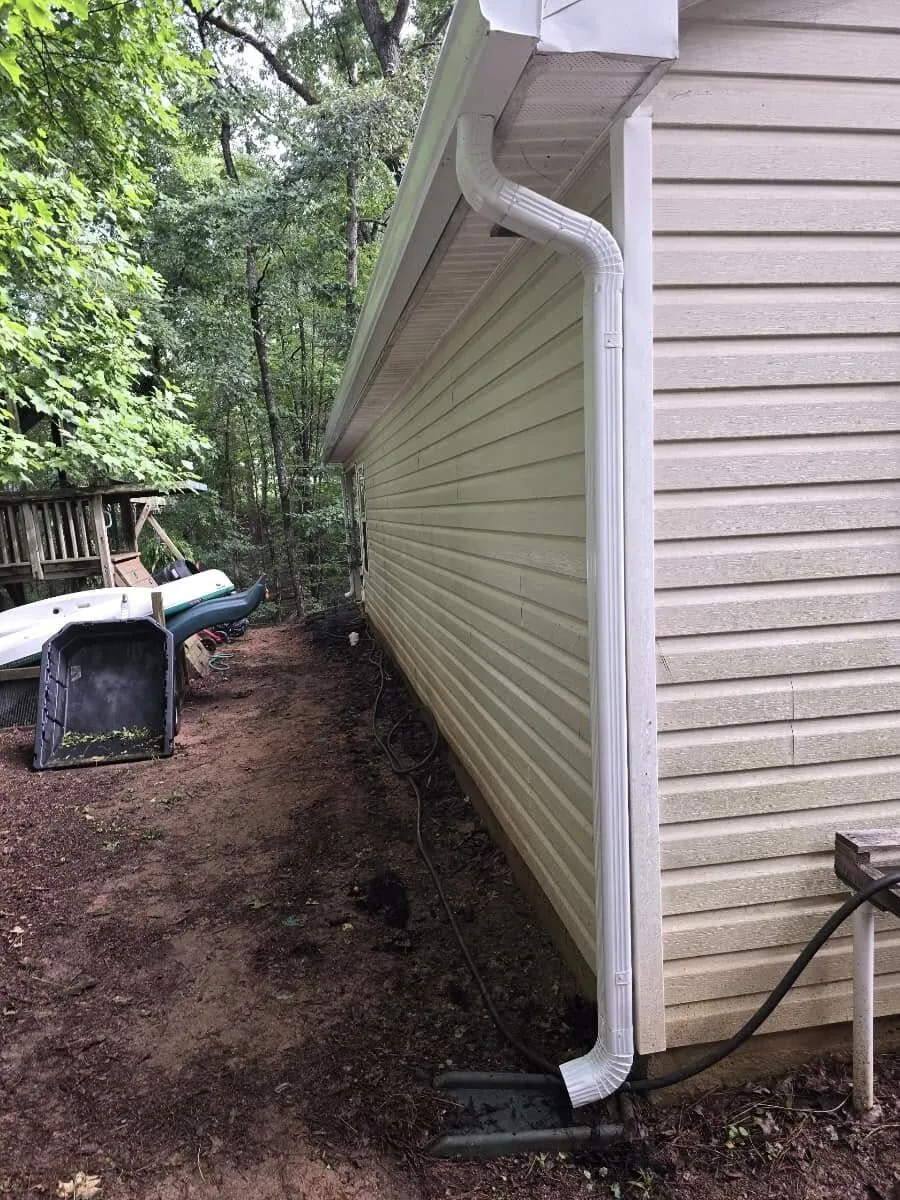 Close detail of a new white gutter downspout running down home siding in Villa Rica GA