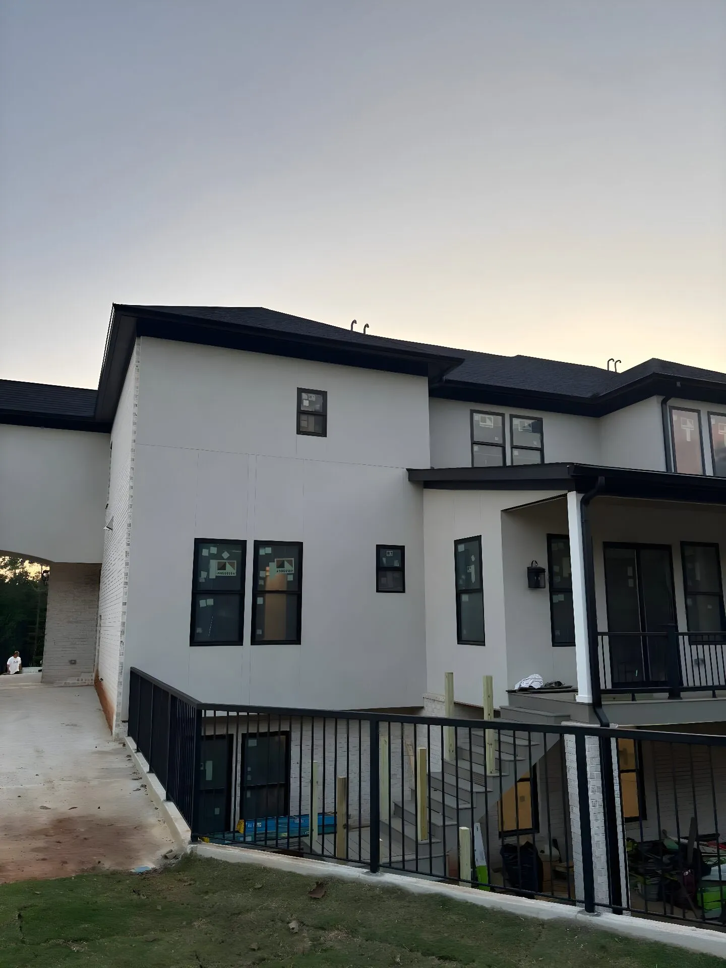 New-construction two-story home at dusk with black gutters and a downspout run along the rooflines