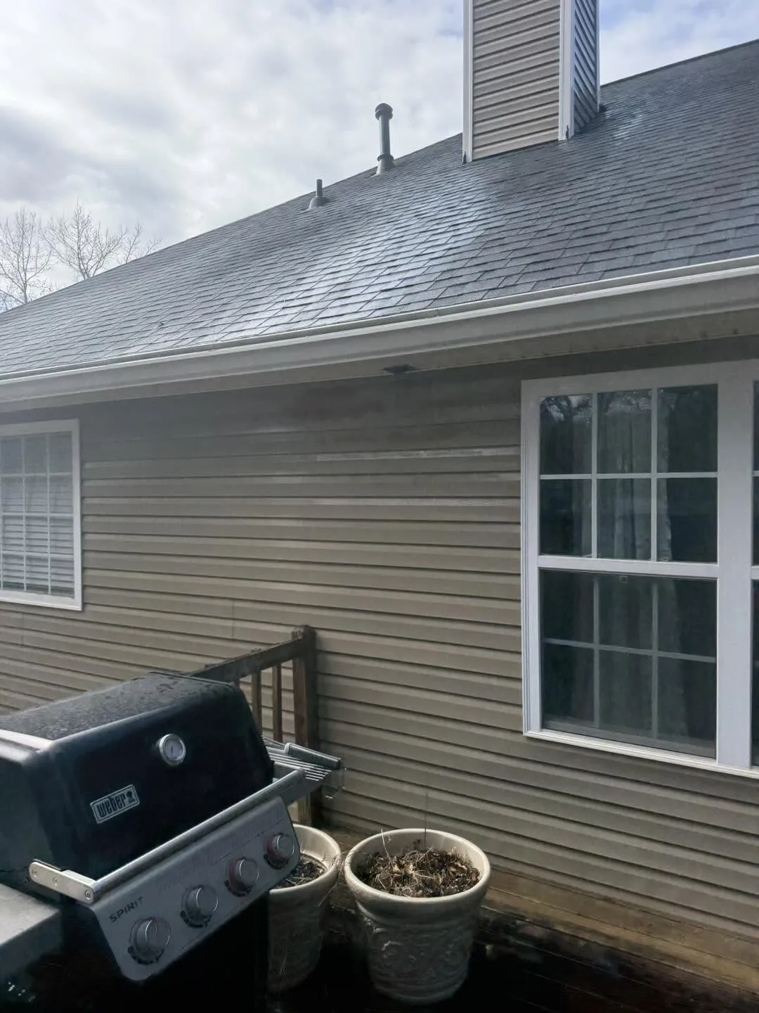 Shaded shingle roofline above grimy tan vinyl siding before a house wash in Villa Rica