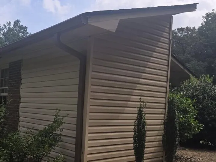 New seamless gutter run along a tan gable end with tidy landscaping in West Georgia