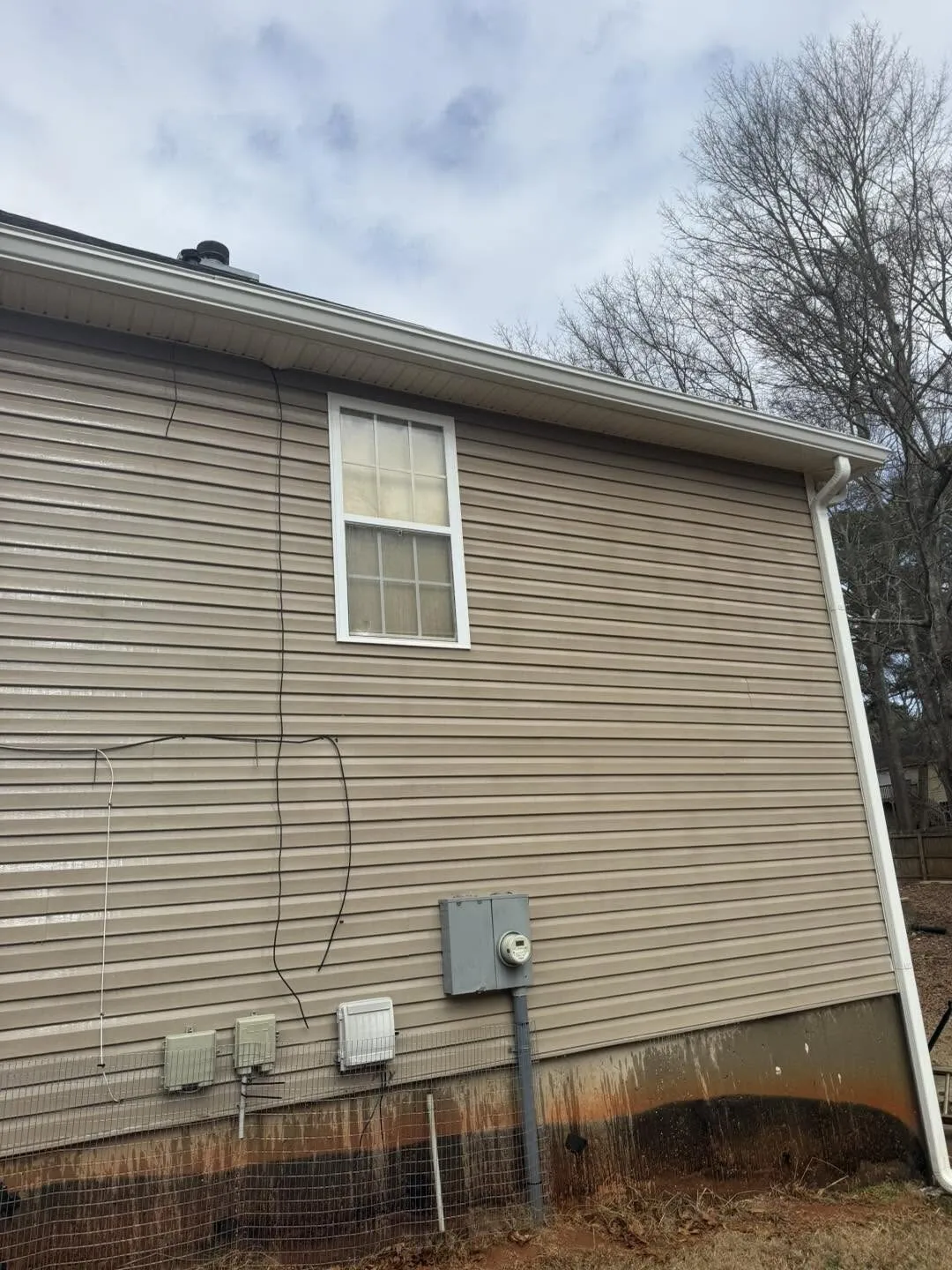 Vinyl siding on a Fairfield Plantation home's lower wall showing dark mildew and rust-toned staining along the base ahead of a pressure washing job