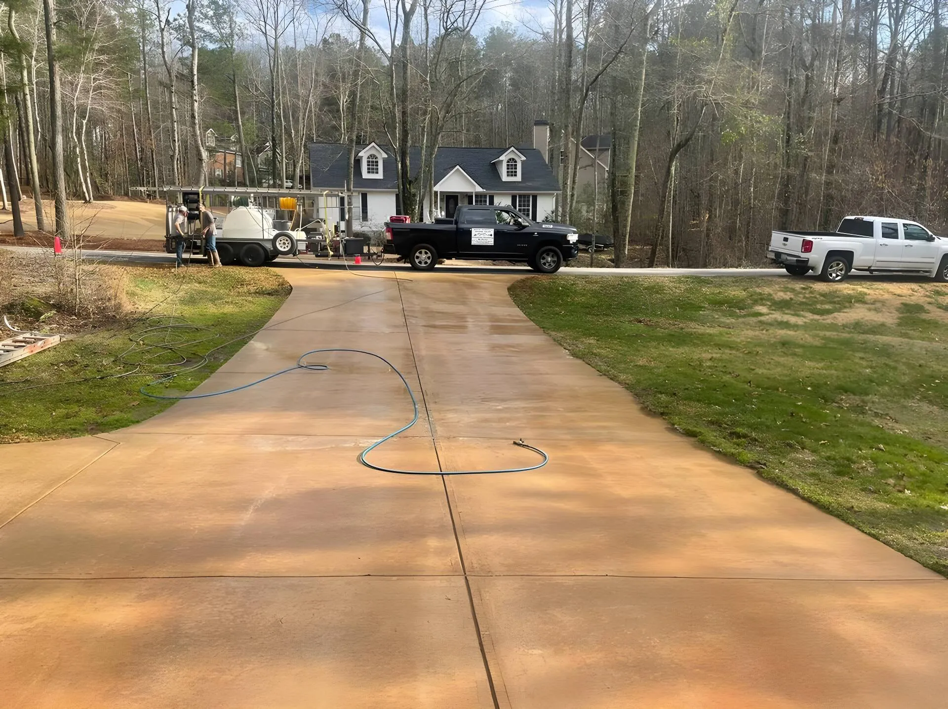 West Georgia Gutter Guys pickup truck and pressure washing trailer rig parked at the top of a wet driveway